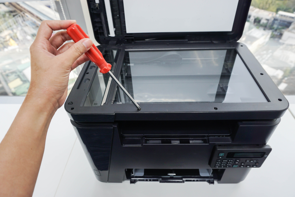 Close up of an office copier with a technician holding a screwdriver signifying copier repair.
